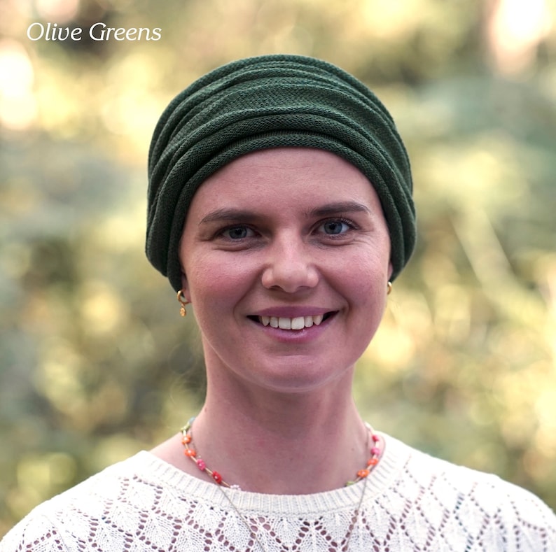 Puede incluir: Una mujer con un turbante de color verde oscuro. Est&aacute; sonriendo y lleva un su&eacute;ter de punto blanco.