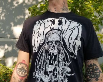May include: Black t-shirt with a white graphic of a skull with teeth and tentacles. The skull is surrounded by the text "WELCOME".
