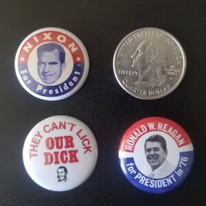May include: Four political campaign buttons and a quarter. The buttons feature images of Richard Nixon and Ronald Reagan, with text that reads "Nixon for President" and "Ronald W. Reagan for President in '76". One button has the text "They Can't Our Dick".