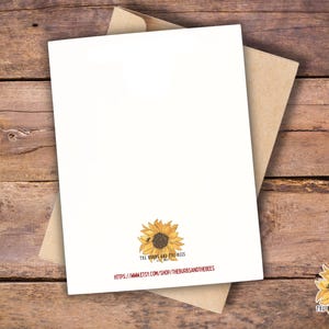 May include: A blank white greeting card with a sunflower illustration and a kraft paper envelope. The card features the text "THE BURBS AND THE BEES" and a website address. The card is set against a rustic wooden background.