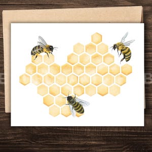 May include: A greeting card featuring a watercolor illustration of a honeycomb with three bees. The honeycomb is yellow and the bees are black and yellow. The card is on a brown envelope, with the words "THE BEES" visible.