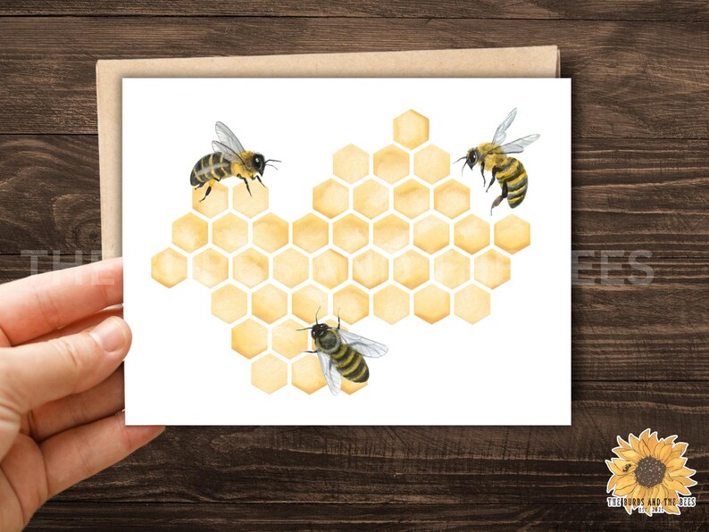 May include: A greeting card featuring a watercolor illustration of three bees and a honeycomb. The bees are yellow and black, and the honeycomb is a light yellow. The card is on a white background.