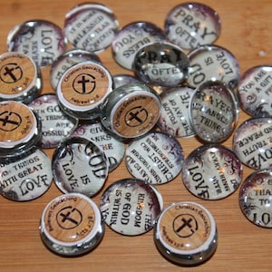 May include: A selection of glass cabochons featuring religious quotes and cross motifs. Some have wooden tops with "Christian Geocaching." Quotes include "Love," "Pray Often," and "Give Thanks to the Lord." Measurements are not applicable.
