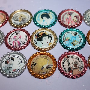 May include: A collection of 15 round, colorful bottle caps with images of Japanese culture and the text "Geocaching Japan" or "Geocaching Okinawa".