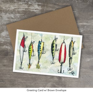May include: A greeting card featuring a watercolor painting of seven colorful fishing lures hanging from a string. The lures are various shades of red, green, blue, yellow, and white.