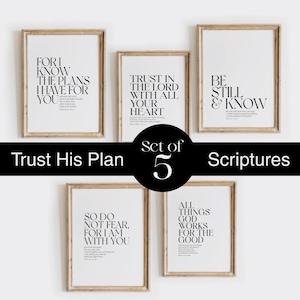 May include: A set of five framed art prints with inspirational quotes in black text on a white background. The frames are a light brown color. The text includes phrases like "Trust in the Lord" and "Be Still & Know". The set is labeled "Trust His Plan" and "Set of 5 Scriptures".