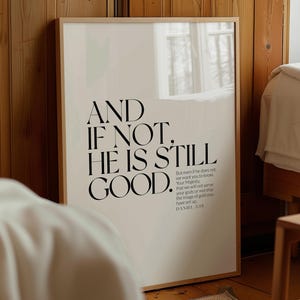 May include: A framed poster with the text "AND IF NOT, HE IS STILL GOOD." in black, bold font. The poster also includes a Bible verse from Daniel 3:18. The background is a cream colour, and the frame is a light wood.