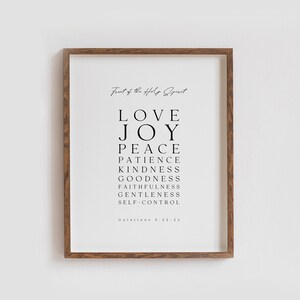 May include: A black and white printable wall art print with the text "Fruit of the Holy Spirit" and a list of the fruits of the Holy Spirit: Love, Joy, Peace, Patience, Kindness, Goodness, Faithfulness, Gentleness, Self-Control. The text "Galatians 5:22-23" is at the bottom of the print.