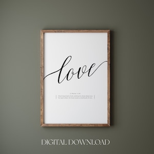 Op de afbeelding: Een ingelijste print met het woord "love" in elegant zwart schrift. Daaronder staat een Bijbelvers uit 1 Petrus 4:8. De print zit in een houten lijst en heeft onderaan de tekst "DIGITALE DOWNLOAD".