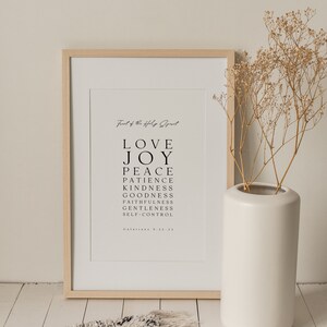 May include: A framed print with a white background and black text. The text reads "Fruit of the Holy Spirit" and lists the following words: Love, Joy, Peace, Patience, Kindness, Goodness, Faithfulness, Gentleness, Self-Control. The text also includes the scripture reference "Galatians 5:22-23".