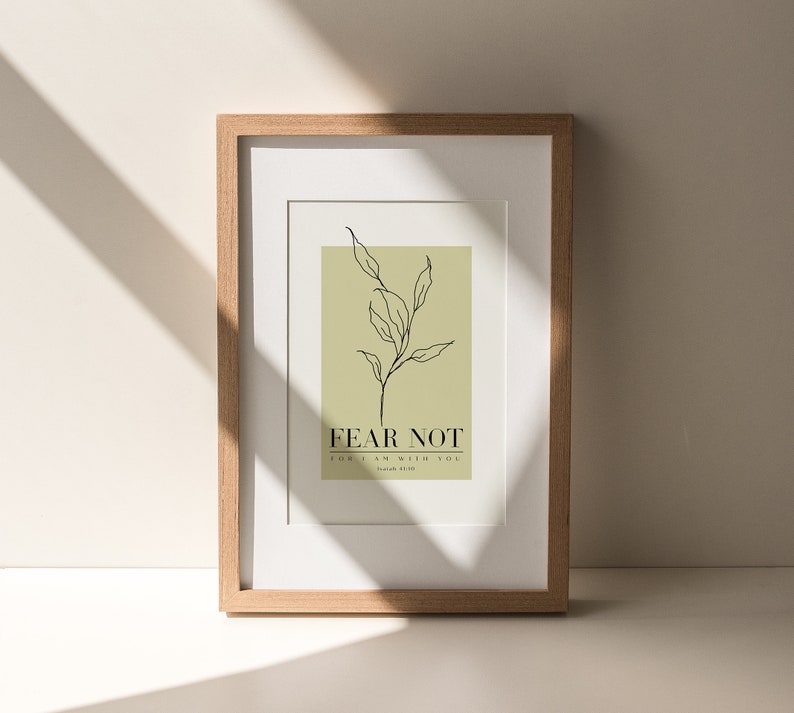 May include: A framed print with a minimalist line drawing of a plant on a light green background. The text "FEAR NOT FOR I AM WITH YOU" is below the plant drawing. The text "Isaiah 41:10" is below the quote.