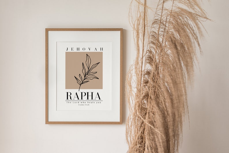 May include: A framed print with a brown background and a black line drawing of a leaf. The text "Jehovah Rapha" is printed in black with the phrase "The Lord who heals you" in smaller font below.