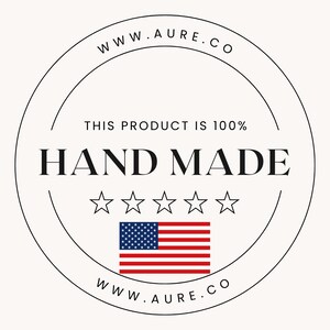 May include: A black and white circular stamp with the text "WWW.AURE.CO" at the top and bottom. The text "THIS PRODUCT IS 100% HAND MADE" is in the center of the stamp. Five white stars are below the text. An American flag is below the stars.
