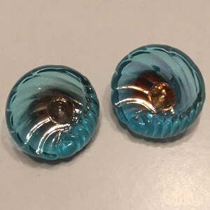 May include: Two blue glass buttons with a gold center. The buttons have a swirl design.