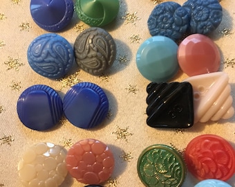 May include: A collection of 18 vintage buttons in various colors, patterns, and materials. The buttons are arranged in pairs and include blue, green, pink, red, black, and white buttons.