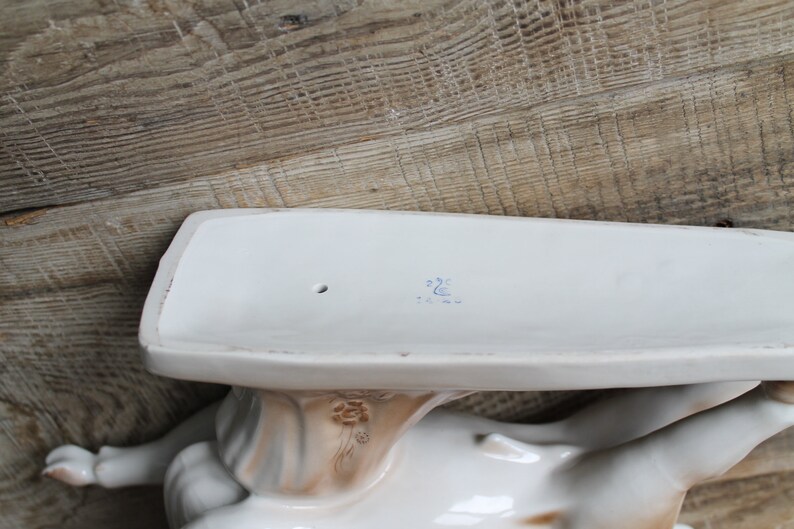 May include: White porcelain figurine of a woman holding a tray. The tray has a blue mark on the bottom that reads "22C".