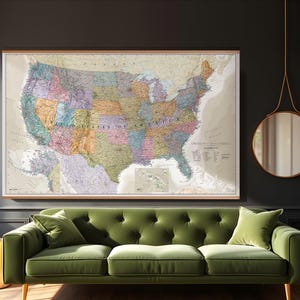 May include: A framed map of the United States of America hangs above a green velvet sofa. The map is detailed with state boundaries and color-coded regions. A round mirror and gold side tables complete the room.