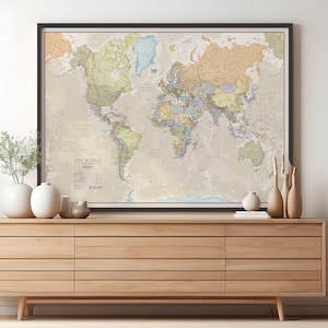 May include: A framed world map with a beige background and colorful country borders. The map is titled "The World" and includes a legend with various symbols and abbreviations. The map is hanging on a wall above a wooden dresser.