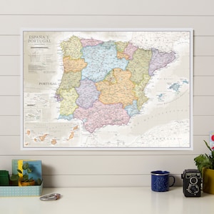May include: A framed map of Spain and Portugal, featuring detailed geographical and political information. The map is in a white frame and displays various regions with different colors. Text on the map includes "España y Portugal" and other geographical terms.