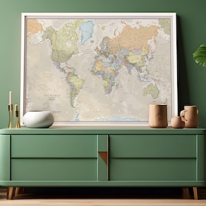May include: A framed world map with a beige background and colorful country borders. The map is hanging on a green wall above a green dresser with two drawers. There are three gold candlesticks and a white ceramic bowl on the dresser.