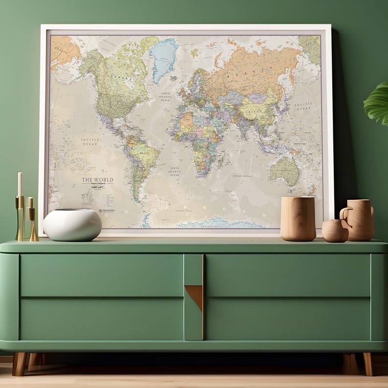 May include: A framed world map with a beige background and colorful country borders. The map is hanging on a green wall above a green dresser with two drawers. There are three gold candlesticks and a white ceramic bowl on the dresser.
