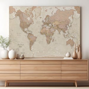 May include: A vintage-style world map with a beige background and brown and pink details. The map is framed and hanging on a wall above a wooden dresser.