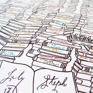 May include: A wedding guest book in the shape of a stack of books with names written on each book. The book is open and has the date "July 17" written on the left page and the name "Steph" written on the right page. The top of the book has the words "Mr & Mrs" written on it.
