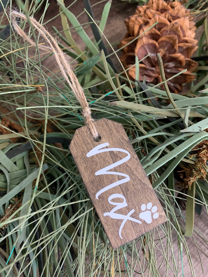 May include: A wooden Christmas ornament with the name "Max" and a paw print in white paint.