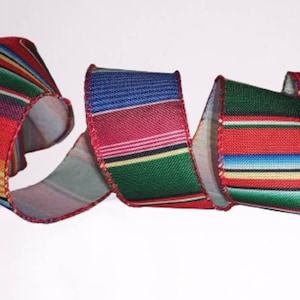 May include: A colorful striped ribbon with red, green, blue, yellow, and white stripes. The ribbon is woven with a textured fabric and has a red edge.