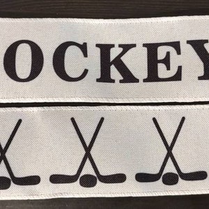 May include: White ribbon with the word "HOCKEY" printed in black. The ribbon has a repeating pattern of hockey sticks and pucks.
