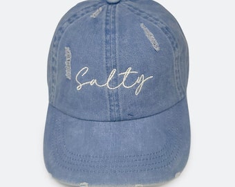 May include: A light blue denim baseball cap with a distressed look and the word "Salty" embroidered in white on the front.