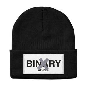 May include: Black beanie hat with a white rectangular patch. The patch features the word "BINARY" with a gray "X" over it, and the word "GENDER" below. The hat is made of a knitted material.