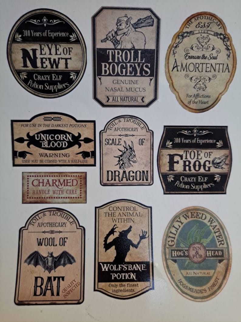 May include: Nine vintage-style potion bottle labels with whimsical illustrations and text. The labels feature names like "Eye of Newt", "Troll Bogeys", "Amortentia", "Unicorn Blood", "Scale of Dragon", "Charmed", "Wool of Bat", "Wolfsbane Potion", "Gillyweed Water", and "Toe of Frog".