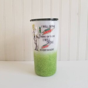 May include: A white and green glitter tumbler with a black lid. The tumbler has a graphic of a cartoon character holding a Mountain Dew bottle and the text "I will drink Mountain Dew here or there I will drink Mountain Dew everywhere".