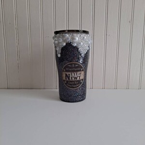May include: A black glitter tumbler with a white pearl rim and a label that reads "11 Years of Experience Eye of Newt Crazy Elf Potion Supplies".