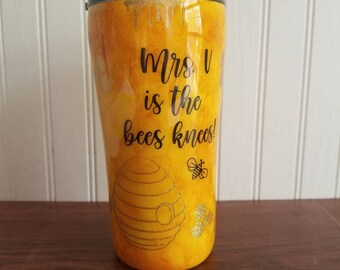May include: A yellow tumbler with a black lid and a black design that says "Mrs. V is the bees knees!" with a bee and a honeycomb design.