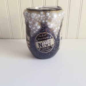 May include: A black glitter tumbler with a gold rim and white pearl accents. The tumbler has a label that reads "Eye of Newt" with the text "300 Years of Experience" and "Crazy Elf Potion Suppliers".