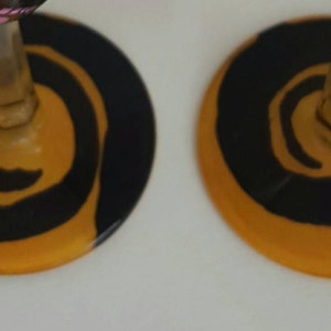 Pode incluir: Duas ta&ccedil;as de vinho com desenhos de espiral preto e laranja na base do copo.
