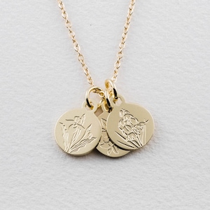 May include: A gold necklace with three round charms featuring engraved floral designs. The charms are attached to a delicate gold chain.