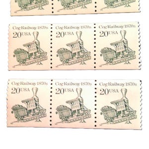 May include: A sheet of vintage postage stamps featuring a cog railway train design. Each stamp is light brown with the text "Cog Railway 1870s" and "20 USA". The stamps are arranged in rows and columns.