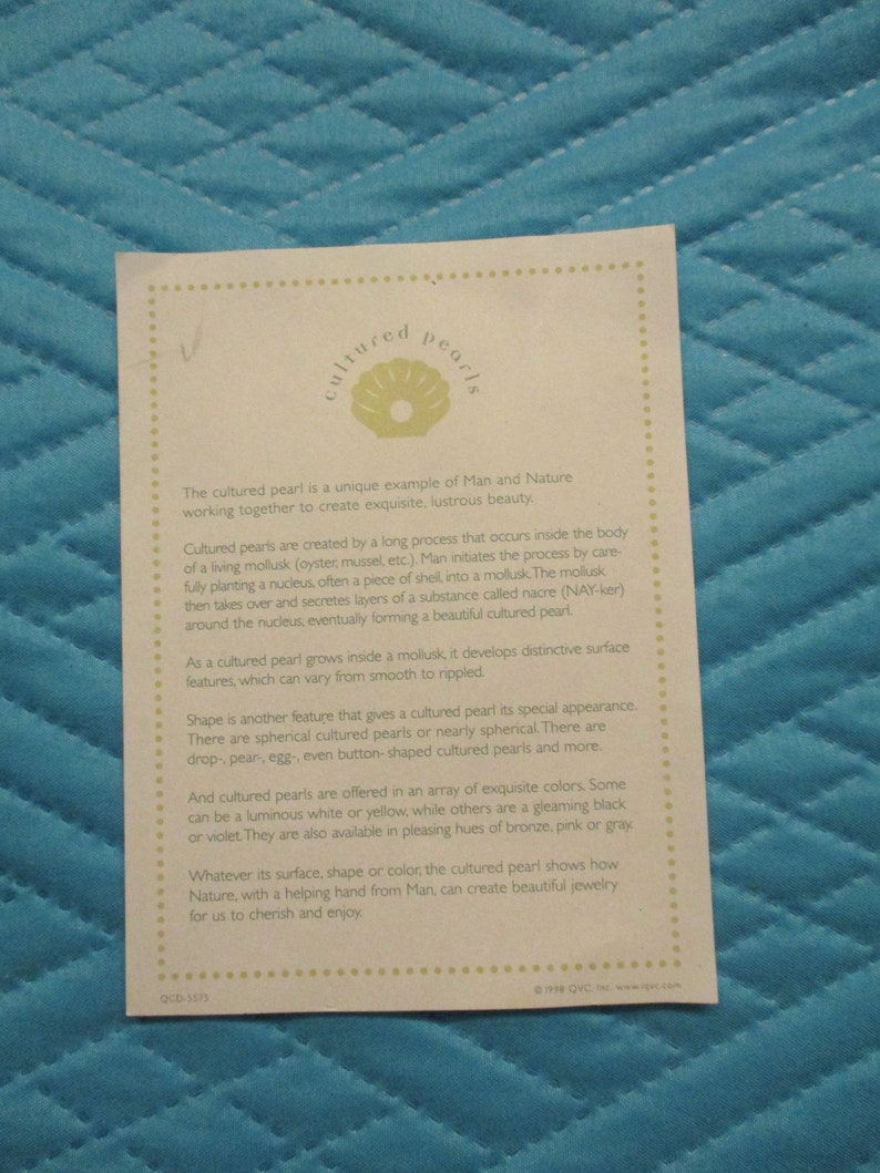 May include: A white card with a green illustration of a seashell and the text "cultured pearls". The card explains how cultured pearls are created by a mollusk and describes the different shapes, colors, and sizes of cultured pearls.
