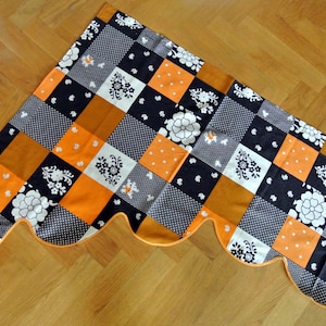 May include: A scalloped valance with a patchwork design featuring black, white, and orange squares with floral patterns.