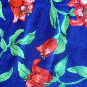 May include: A blue fabric with a red floral pattern. The flowers are lilies and the fabric has the word "Lilium" printed on it.