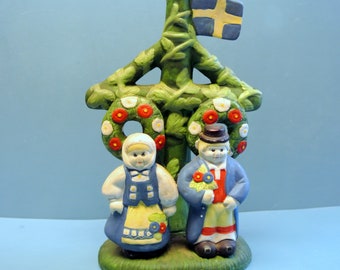 Couple d'art folklorique suédois multicolore en céramique des années 80, vêtu de costumes nationaux suédois, debout près d'un poteau, figurine