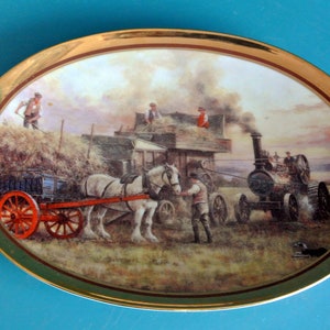 Puede incluir: Una ilustración vintage de una máquina de vapor tirando de un carro tirado por caballos en una granja. La escena está ambientada en un paisaje rural con una paca de heno en el fondo. La máquina de vapor está pintada de rojo y negro, y el caballo es blanco.