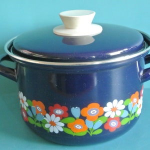 May include: Blue enamel pot with a white lid and floral design. The pot has two handles and a white knob on the lid.