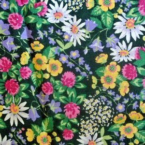 May include: A dark green fabric with a floral pattern. The pattern features white, yellow, pink, and purple flowers. The flowers are arranged in a random pattern.