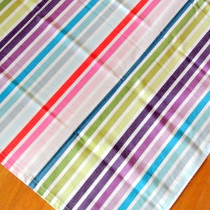 May include: A colorful striped fabric with alternating stripes of white, red, pink, light blue, dark blue, green, and purple.