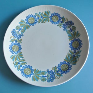 May include: A white ceramic plate with a blue and green floral design around the rim.