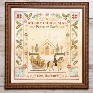 May include: A framed cross-stitch embroidery featuring a winter scene with a church, a person riding a horse, and a sleigh filled with gifts. The text reads Merry Christmas, Peace on Earth, and Bless This Home, surrounded by holly borders.